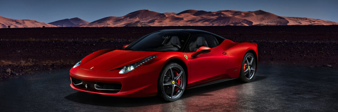 A red Ferrari 458 Italia standing in front of the desert dunes. Engine V8, 4.5L, 570HP. Electronic assembly with Moroccan landscape. Katowice, Poland, 23/12/2013