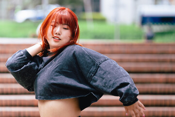 Korean woman with fiery red hair caught in a spontaneous dance moment on city steps