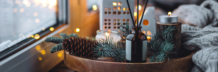 Aroma burning candles, aromatic reed diffuser in glass bottle. Cozy Christmas atmosphere at home....