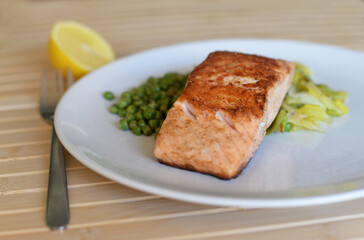 Home cooked meal with fried salmon, stewed green peas and grilled leek. Selective focus