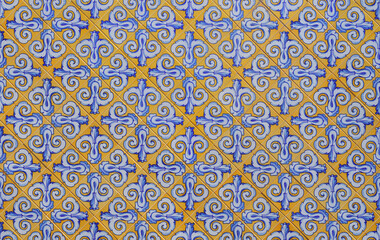Traditional Spanish ceramic wall tiles in a seamless yellow, blue and white pattern. Architectural background