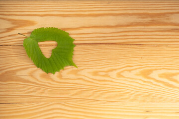 green leaf with heart-shaped cutout on wooden table, blank space on rustic wooden board, mock up healthy lifestyle, Nature therapy, Green living