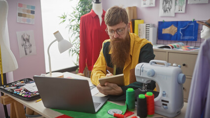 Redhead bearded man in yellow jacket taking notes in a colorful tailor shop with sewing machine and...