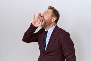 Middle age business man with beard wearing suit and tie shouting and screaming loud to side with hand on mouth. communication concept.