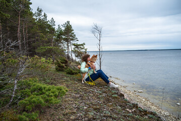 Woman is hugging her Shiba inu dog on the sea shore at  spring in Saaremaa island, Estonia