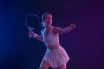 Padel tennis player with racket on tournament. Girl athlete with paddle racket on court with neon colors. Sport concept. Download a high quality photo for design of a sports app or tour events.