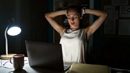 Stressed young woman at her office desk during a late night work session.