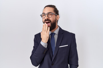Hispanic man with beard wearing suit and tie bored yawning tired covering mouth with hand. restless...
