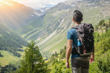 Outdoor sport theme: A hiker with a backpack enjoying the view of the mountains.