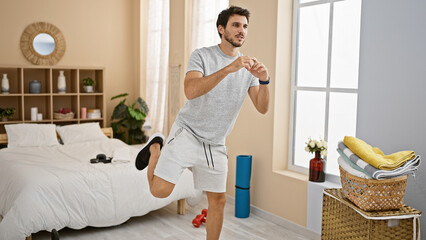 A young hispanic man exercises in a modern bedroom, portraying a healthy lifestyle at home.