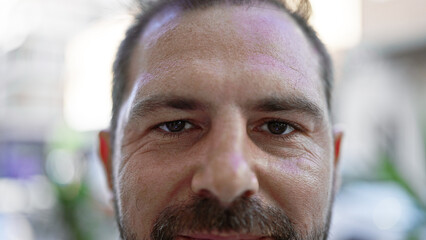 Close-up portrait of a middle-aged hispanic man with grey hair, outdoors against an urban street background.