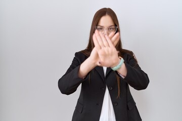 Beautiful brunette woman wearing business jacket and glasses rejection expression crossing arms and...