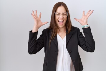 Beautiful brunette woman wearing business jacket and glasses celebrating mad and crazy for success...