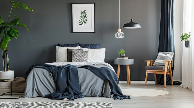 A bedroom with a bed, chair, and a potted plant. The bed is covered with a blue blanket and pillows, and there is a white pillow on top of it. The room has a modern and minimalist design