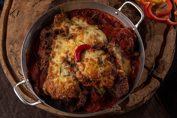 Bife à Parmegiana em panela de alumínio com pimenta decorativa