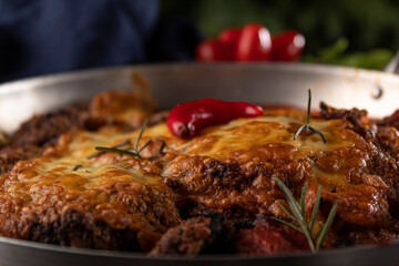 Bife à Parmegiana em panela de alumínio com pimenta decorativa