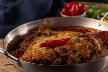 Bife à Parmegiana em panela de alumínio com pimenta decorativa
