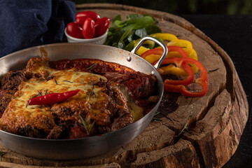 Bife à Parmegiana em panela de alumínio com pimenta decorativa