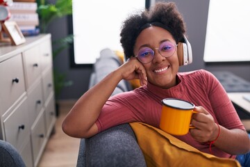 African american woman listening to music drinking coffee at home