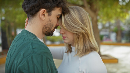 Intimate couple embracing in a tranquil outdoor park, portraying love and a deep connection between a young man and woman.