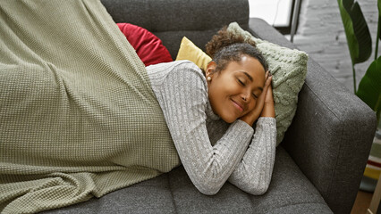 Young african american woman sleeping peacefully on a couch in a cozy living room interior.