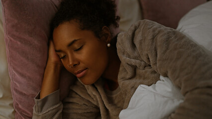 Serene young woman relaxing in bedroom with eyes closed, exuding calmness and comfort indoors.