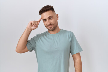 Fototapeta premium Hispanic man with beard standing over white background smiling pointing to head with one finger, great idea or thought, good memory