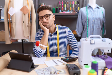 Hispanic man with beard dressmaker designer working at atelier thinking looking tired and bored...