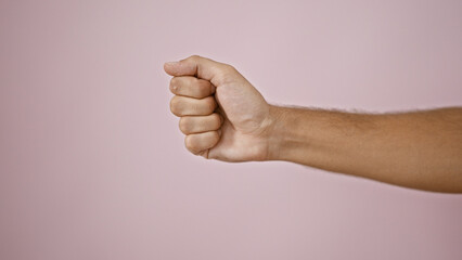 Close-up of a young man's clenched fist against an isolated pink background, depicting strength and...