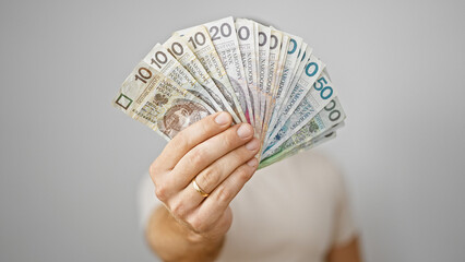 Handsome bearded man holding fan of polish zloty banknotes against a white background, symbolizing...