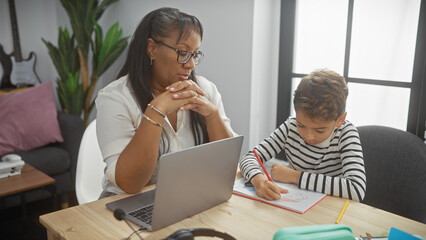 A contemplative woman and focused boy engage in homework activities in a modern living room,...