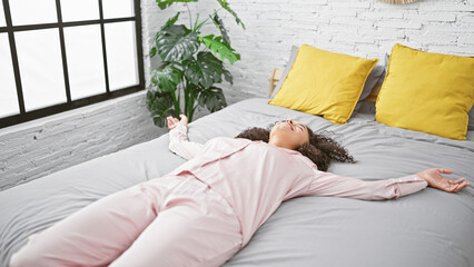 Awake and energized, beautiful young hispanic woman stretching arms in bed, radiating relaxation in...