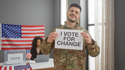 A smiling man in military uniform holds a 'vote for change' sign in a room with an american flag...