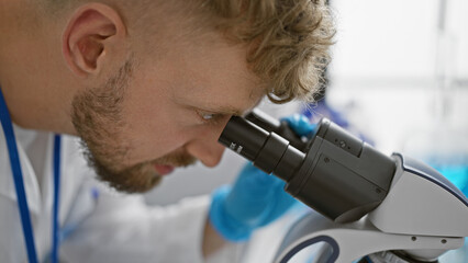 Caucasian man with beard using microscope in laboratory setting