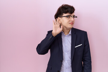 Young non binary man with beard wearing suit and tie smiling with hand over ear listening an hearing to rumor or gossip. deafness concept.