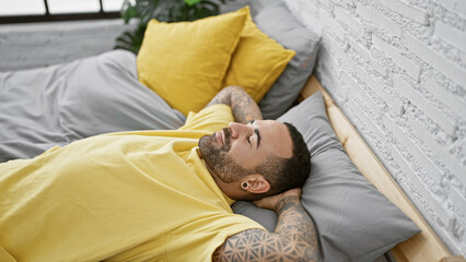 A relaxed bearded man resting comfortably in a modern bedroom with yellow accents and wood...