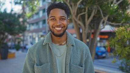 Handsome black man smiling outdoors in a city environment, exuding casual urban style and...