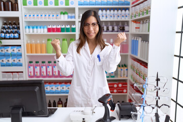 Middle age chinese woman working at pharmacy drugstore screaming proud, celebrating victory and...