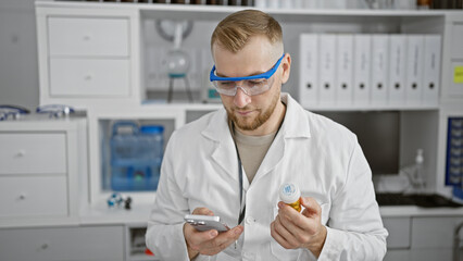 Young caucasian man in lab coat using smartphone and holding pill bottle inside a laboratory.