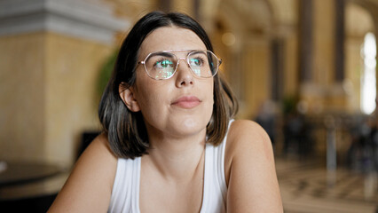 Young beautiful hispanic woman sitting on the table looking serious at cafeteria