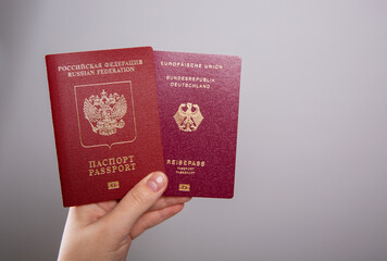 Close up of a female hand holding a German and a Russian passport
