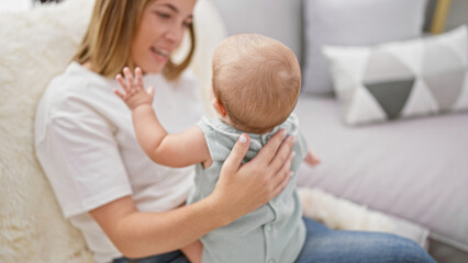 Obraz premium Mother's loving smile, engaged in joyful laughter while sitting together with daughter on sofa at home amidst casual indoor lifestyle