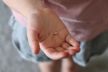 close-up of childs open hand, gently cradling small, fallen baby tooth, blurred background....