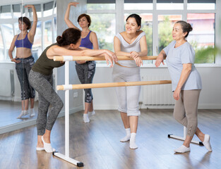 Group of beginner female dancers relax during dance training at barre