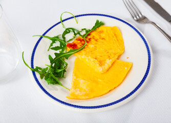 Tender and lush, slices of omelet are laid out on plate, decorated with rucola. Continental...
