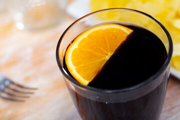 Glass of vermouth with slice of orange served with chips for snack