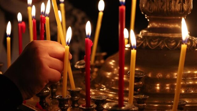Hand placing a burning candle on a candilia on Easter night