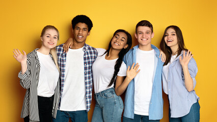 A group of multiethnic teenagers are standing next to each other, facing the camera. They are casually dressed and appear to be engaged in conversation or posing for a picture.