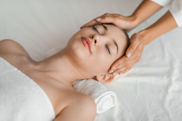 A young blonde woman enjoys a relaxing facial massage at a spa, embodying serenity and tranquility...