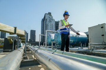 A young engineer checks equipment on a rooftop amidst urban skyline, clipboard in hand, ensuring...